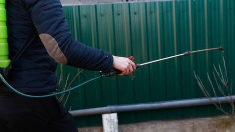 Técnico con máscara y equipo de protección completo fumigando el exterior de una vivienda durante un tratamiento contra pulgas y garrapatas en León Técnico con máscara y equipo de protección completo fumigando el exterior de una vivienda durante un tratamiento contra pulgas y garrapatas en León
